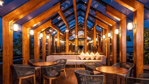 A wooden deck with wicker furniture and a glass ceiling. - DoubleTree by Hilton Weerawila Rajawarna Resort (Weerawila)