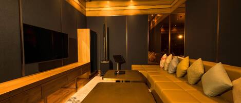 A modern living room with a large flat-screen TV, a sofa with cushions, a coffee table, and a patterned rug.