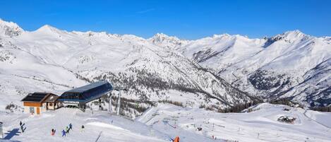 A ski resort with a snow-covered mountain backdrop, a lodge, and a ski lift.