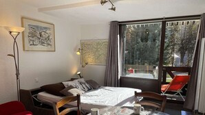 A cozy room with a bed, a table with two mugs, a red chair, and a window with a view of trees. - Cozy studio with mountain nook for 4 people in Chantemerle (Saint-Chaffrey)
