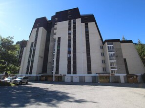 A multi-story building with a modern architectural design, featuring a mix of dark and light facades, and a parking area in front. - Cozy apartment for 6 with balcony and parking, near slopes (La Salle-les-Alpes)