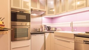 Une cuisine moderne dotée d’appareils électroménagers en acier inoxydable, de meubles blancs et d’un revêtement mural rose.