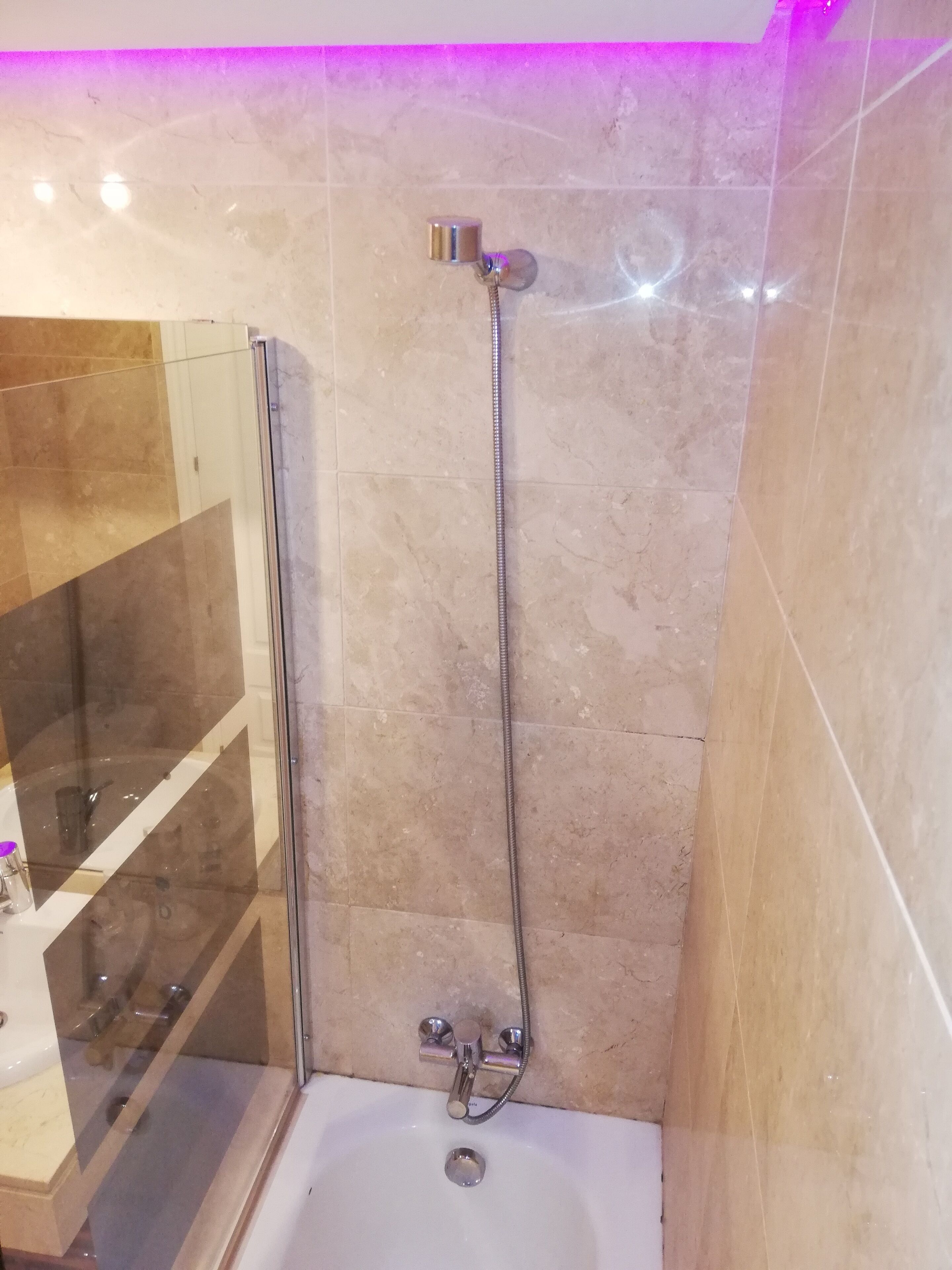 Une salle de bain moderne avec une douche à parois de verre, une baignoire blanche et un pommeau de douche à main.