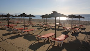 A beach with sun loungers and thatched umbrellas. - Apartment cozy in quiet area near of beaches and shops (Manilva)