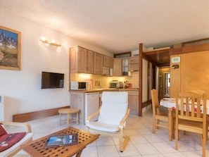 A compact living space with a kitchenette, a dining area, and a seating area with a table and chairs.