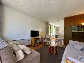 Una sala de estar con sofá, sillas, televisor y un mueble de madera.