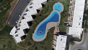 Vue aérienne d’un hôtel doté d’une grande piscine, de plusieurs bâtiments et d’un parking.