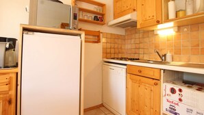 A compact kitchen with wooden cabinets, a white refrigerator, a stove, and a microwave. - Mountain Area Studio for 4 in Chantemerle, Serre-Chevalier (Saint-Chaffrey)