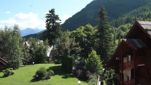 A mountain lodge with a well-maintained garden, wooden cabins, and a view of the surrounding forest and mountains. - Mountain Area Studio for 4 in Chantemerle, Serre-Chevalier (Saint-Chaffrey)