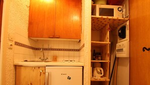 Een kleine keuken met een koelkast, magnetron en een spoelbak.