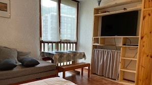 Een gezellige kamer met een bed, een bank, een tafel en een televisie.