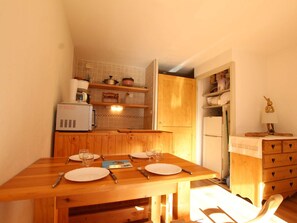 Una cocina compacta con armarios de madera, microondas integrado y un refrigerador.