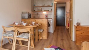 A compact kitchen with wooden furniture, a washing machine, and a microwave.