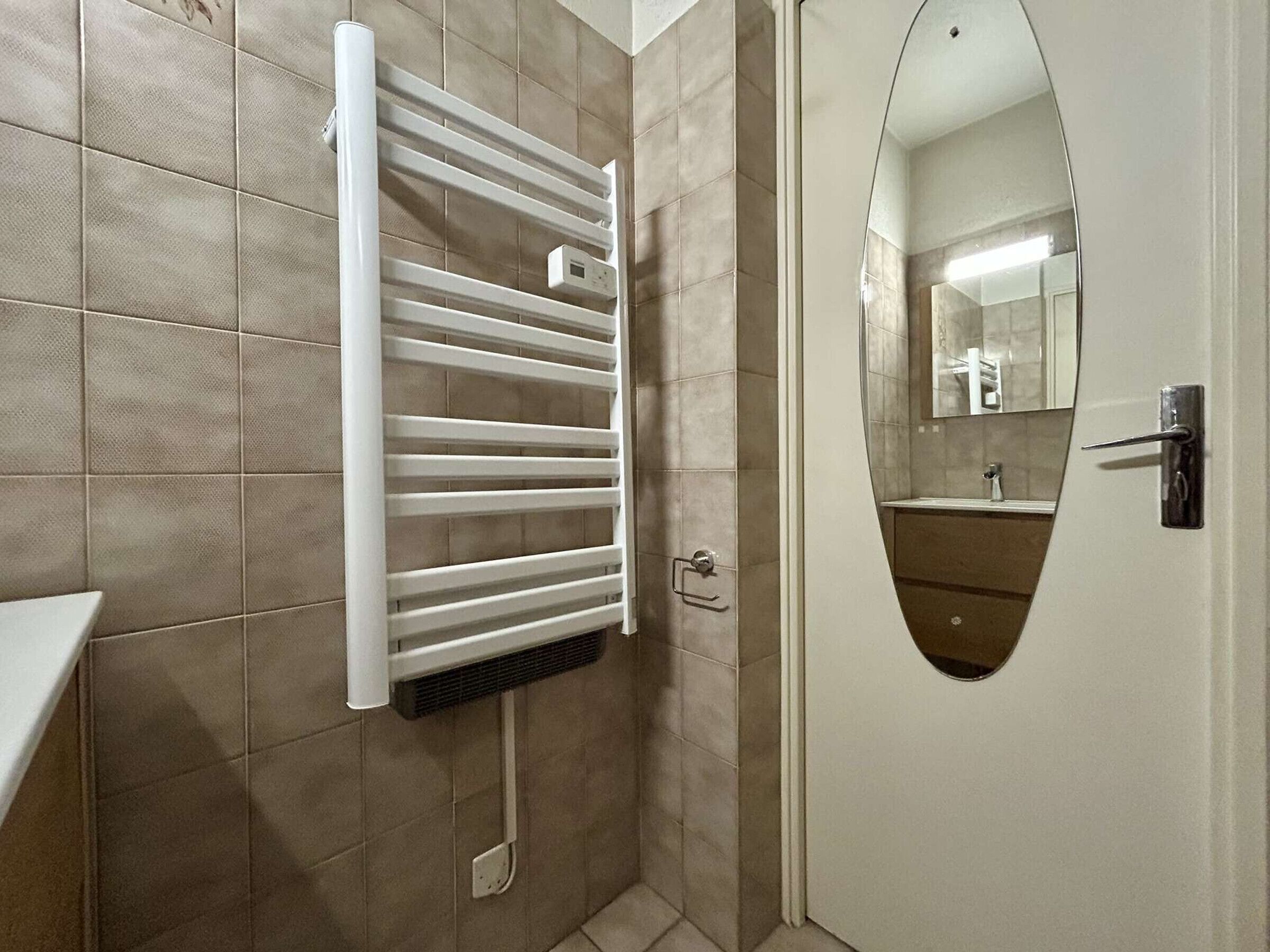 A bathroom with a white towel rack, a mirror, and a door.