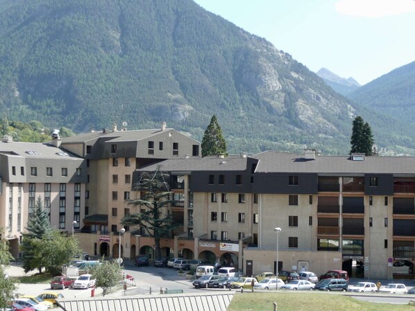 A multi-story hotel with a parking lot in front, surrounded by mountains.