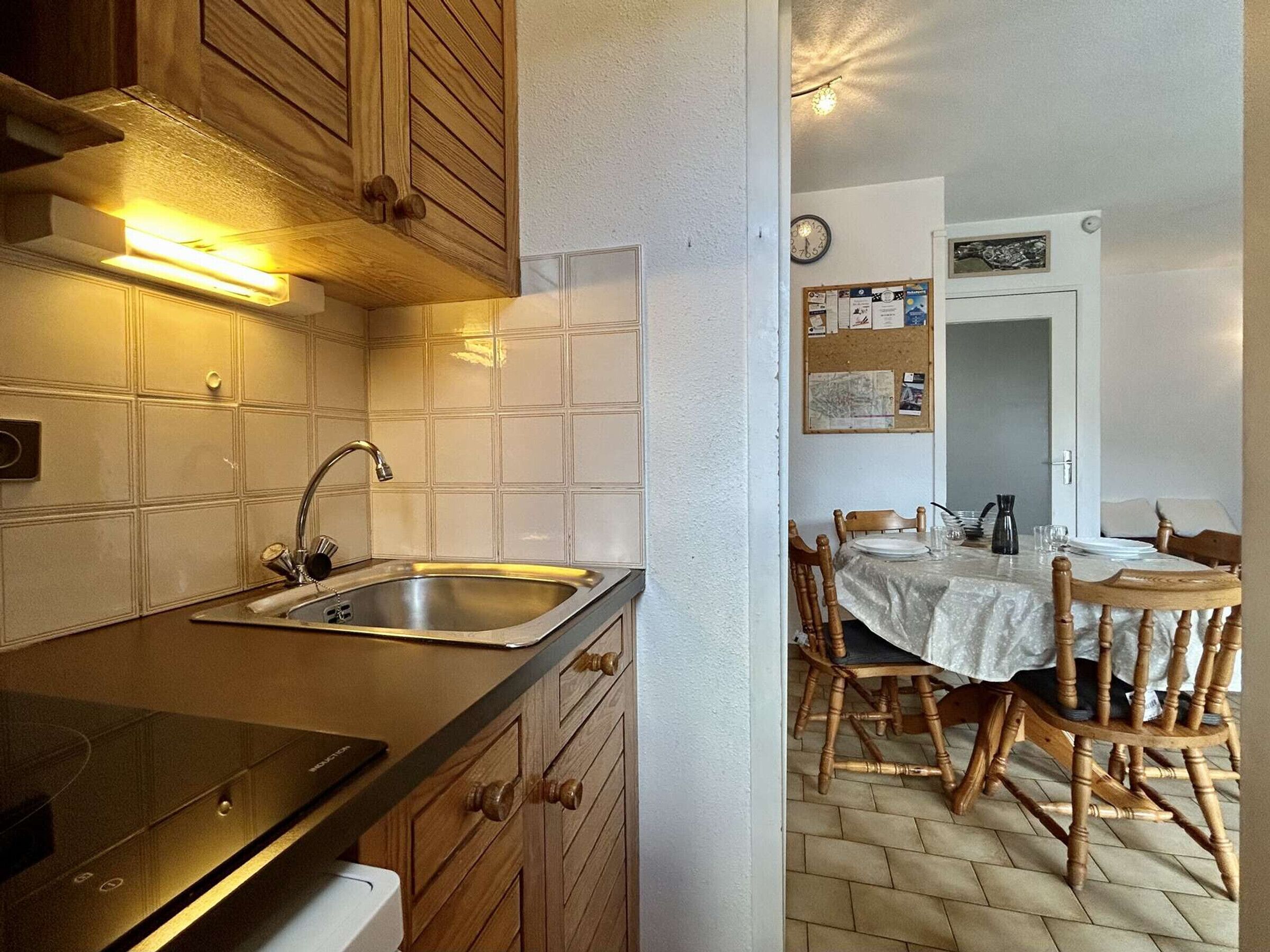 Una cocina con un lavamanos, armarios de madera, una estufa y un comedor con una mesa y sillas.