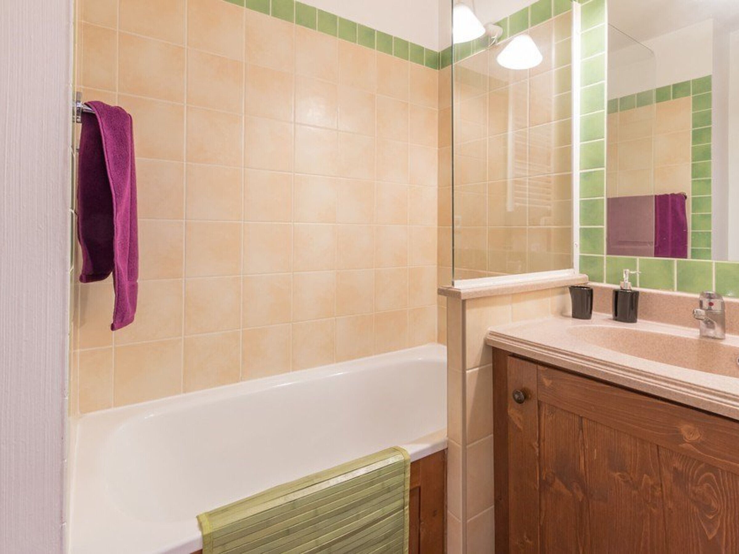 Un bagno con una vasca, un mobile bagno in legno, uno specchio e un asciugamano verde.