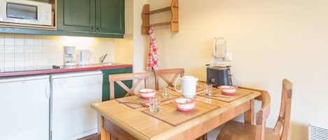 Una cocina con armarios de madera, microondas, cafetera y hervidor sobre la encimera.