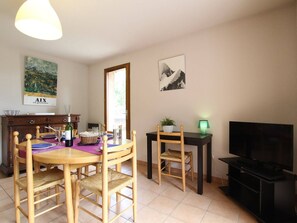Un comedor con una mesa y sillas de madera, un televisor y obras de arte en las paredes.