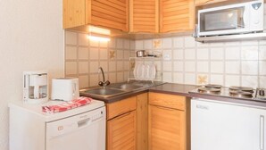 A compact kitchen with wooden cabinets, a microwave, a dishwasher, and a coffee maker. - Cozy 2-Room Apartment with Mountain Views, Balcony & Close to Ski Lifts in Le Monêtier-les-Bains (Le Monêtier-les-Bains)