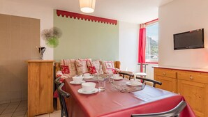 A dining area with a red table, chairs, and a wooden cabinet. - Cozy 2-Room Apartment for 4-6, Near Prorel Cable Car, South-Facing Balcony, Ski Locker (Briançon)