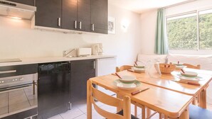 A modern kitchen with dark cabinets, a built-in oven, and a dining area with a wooden table and chairs. - 2-Room Apartment - Sleeps 6, Near Prorel Lift and Briançon Center (Briançon)