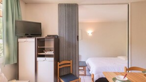 A hotel room with a bed, a desk with a chair, a television, and a wardrobe. - 2-Room Apartment - Sleeps 6, Near Prorel Lift and Briançon Center (Briançon)