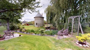 A stone tower, a wooden pergola, and a well-maintained garden with a pond.