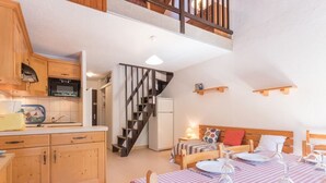 Una cocina acogedora con armarios de madera y una zona de comedor con manteles a cuadros.