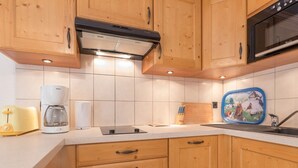 Una cocina con gabinetes de madera, microondas, cafetera y tostadora.