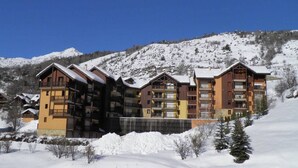 A multi-story hotel with balconies, set in a snowy mountainous area. - Duplex for 6 in Serre-Chevalier - Chantemerle (Saint-Chaffrey)