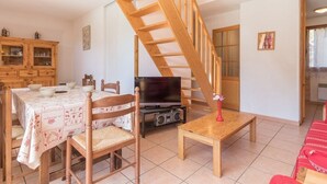 A dining area with a wooden staircase, a television, and a cabinet. - Duplex for 6 in Serre-Chevalier - Chantemerle (Saint-Chaffrey)