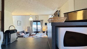 A compact living space with a kitchenette, a dining area, and a sofa. - Spacious Triplex 4 rooms, sleeps 7, near slopes, parking, quiet (Le Monêtier-les-Bains)