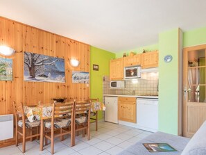 Uma cozinha compacta com armários de madeira, micro-ondas e uma pequena área de refeições com cadeiras e mesa.