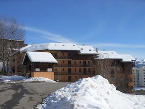 Um edifício de vários andares com telhado coberto de neve, uma placa indicando propriedade privada e céu claro.