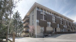 A modern multi-story building with a flat roof, large windows, and a central staircase.