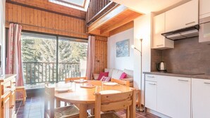 A cozy wooden cabin with a dining area, a kitchen, and a balcony with a view of trees. - Duplex Mezzanine, 6 pers, Serre-Chevalier Chantemerle - Parking, Ski Locker, No Pets (Saint-Chaffrey)