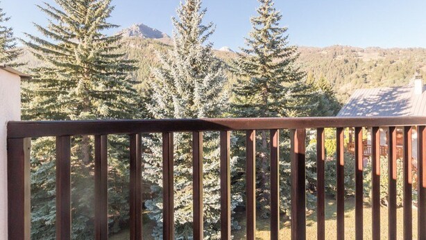A balcony with a wooden railing overlooking a forested area with evergreen trees and a mountain in the background. - Duplex Mezzanine, 6 pers, Serre-Chevalier Chantemerle - Parking, Ski Locker, No Pets (Saint-Chaffrey)