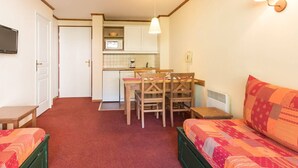 A compact room with a kitchenette, a dining area, and a bed.