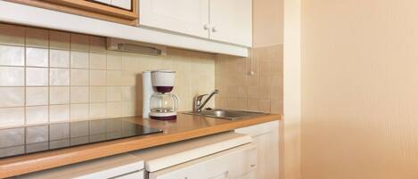 Una cocina con microondas, cafetera, lavavajillas y armarios blancos.