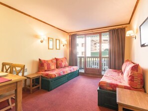 Cozy hotel room with a single bed, desk, and balcony offering a view of the surrounding buildings.