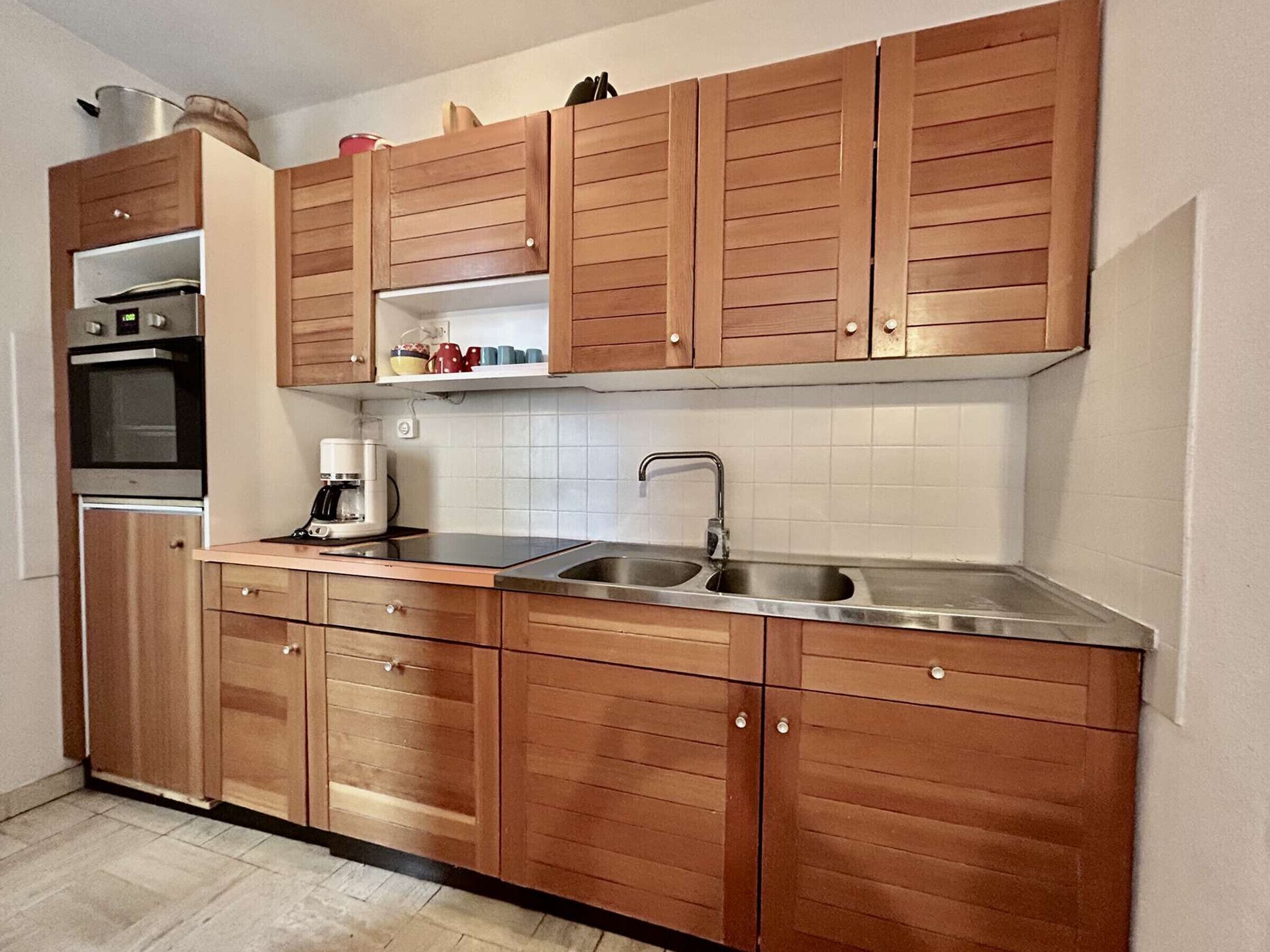 A kitchen with wooden cabinets, a stainless steel sink, and a built-in oven.