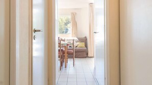 A doorway leading to a room with a dining table, chairs, and a sofa. - Night corner studio for 2/4 people in Briançon near slopes and shops (Briançon)