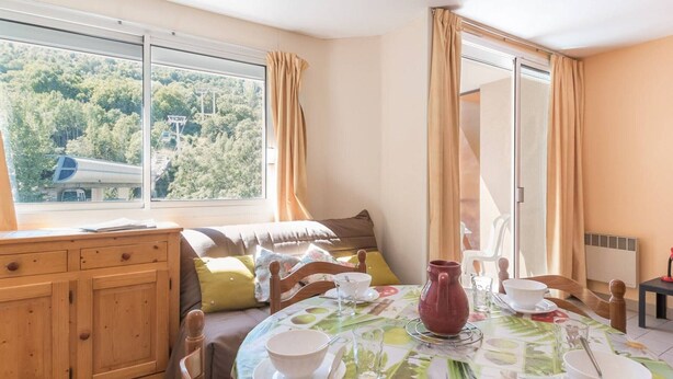 A dining area with a table set for four, a wooden cabinet, and a window with curtains. - Night corner studio for 2/4 people in Briançon near slopes and shops (Briançon)