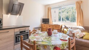 A modern kitchen with a dining area, a TV, and a window with curtains. - Night corner studio for 2/4 people in Briançon near slopes and shops (Briançon)