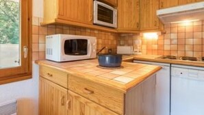A compact kitchen with wooden cabinets, a microwave, a stove, and a dishwasher.