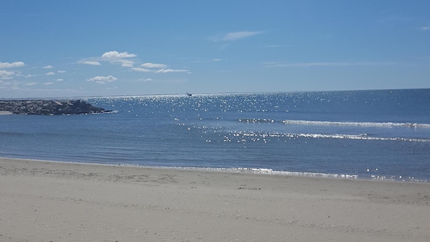 A beach with a clear sky, calm sea, and a rocky outcrop in the distance. - Carnon Centre. Very nice apartment 50 m2 +terrace 25m2, sea and garden view (Mauguio)