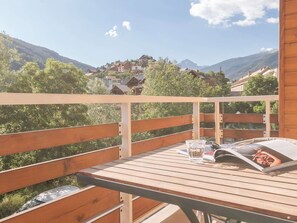 Une terrasse en bois avec une table, un verre d’eau et un magazine.