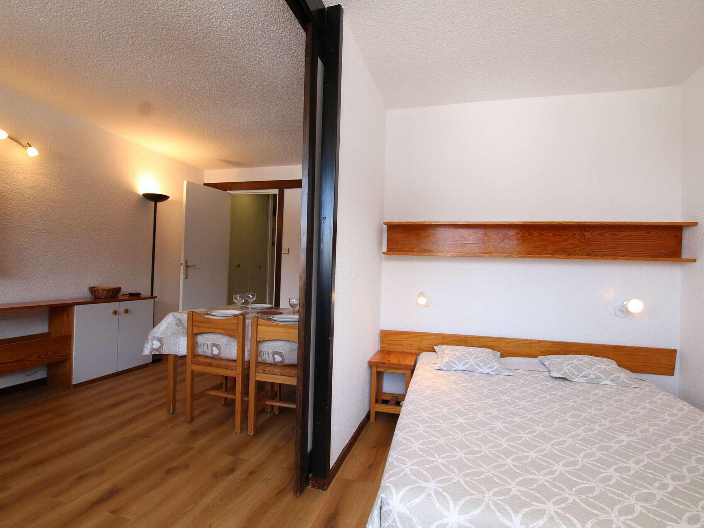 A bedroom with a bed, bedside tables, a desk with a chair, and a mirror.