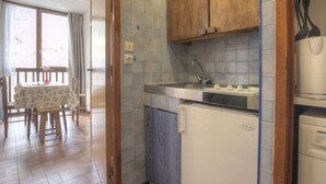 Eine kleine Küche mit Holzausstattung, einem integrierten Spülbecken und einem kleinen Kühlschrank.